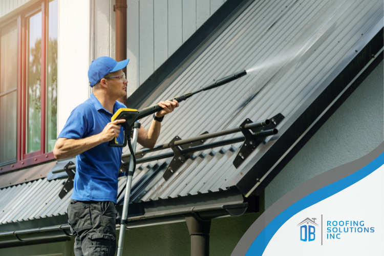 A roofer using a power washer to clean debris from a metal roof in Grass Valley, CA.